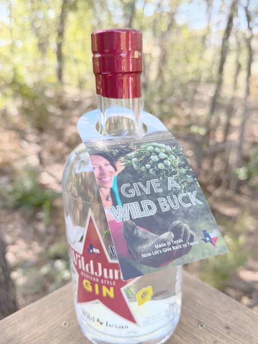 WildJune Gin Bottle on a wooden table with Give a Wild Buck neck hanger